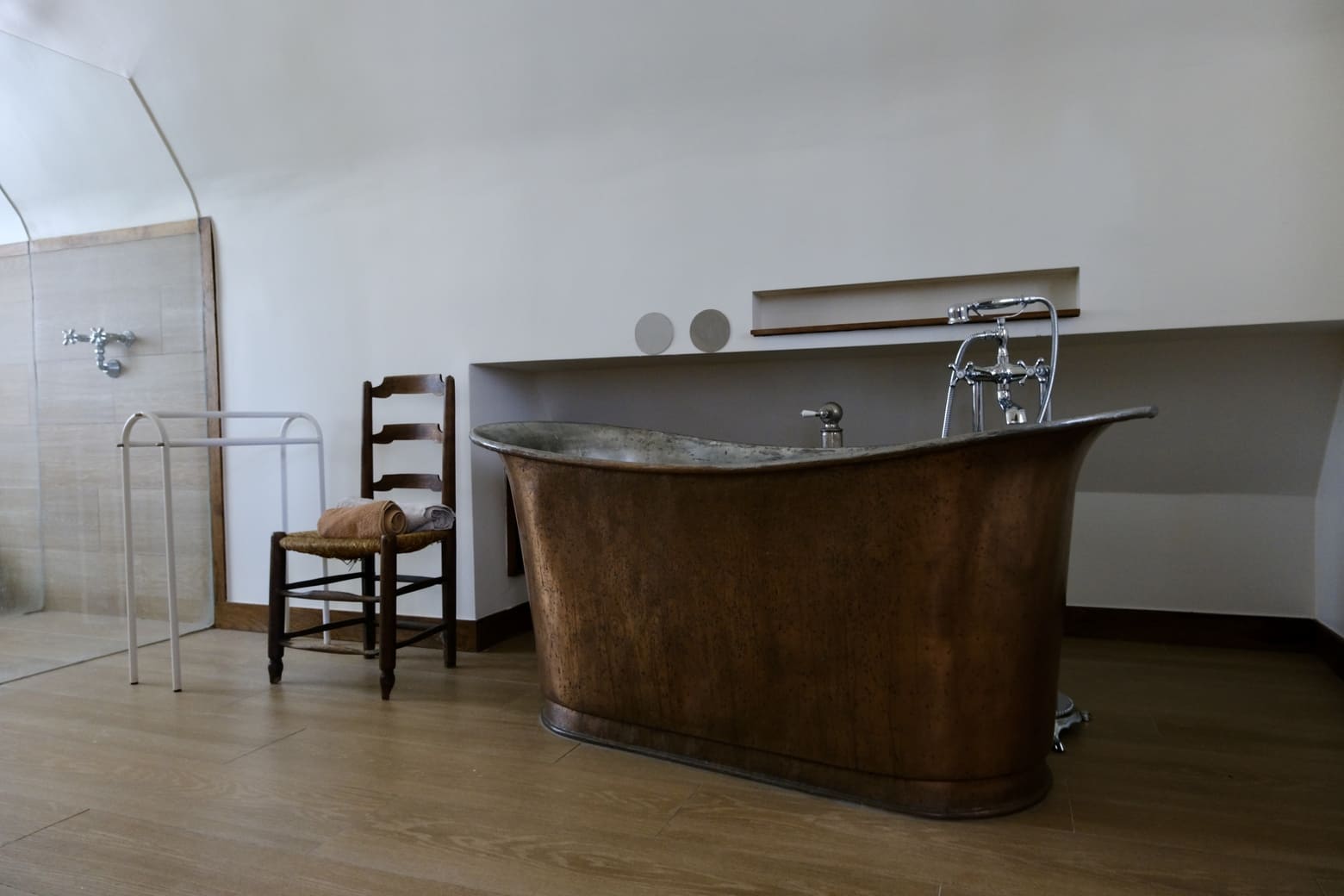 Baignoire en cuivre et chaise en bois dans grande chambre