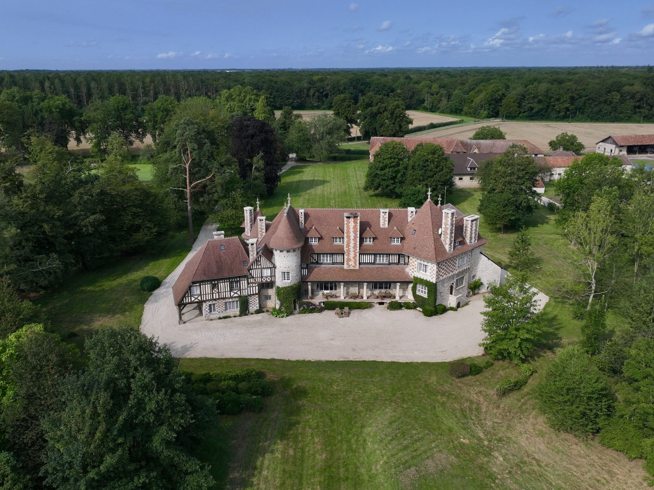 Vue aérienne du manoir entouré de forêts verdoyantes.