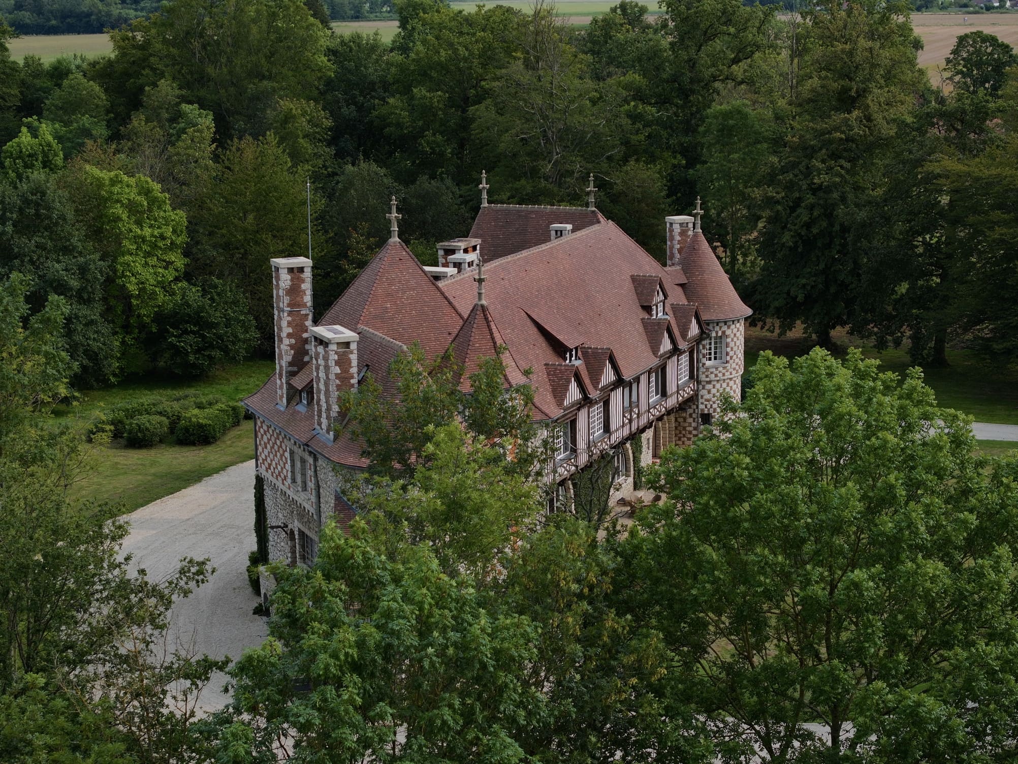 Vue aérienne du manoir avec ses toits en tuiles rouges.